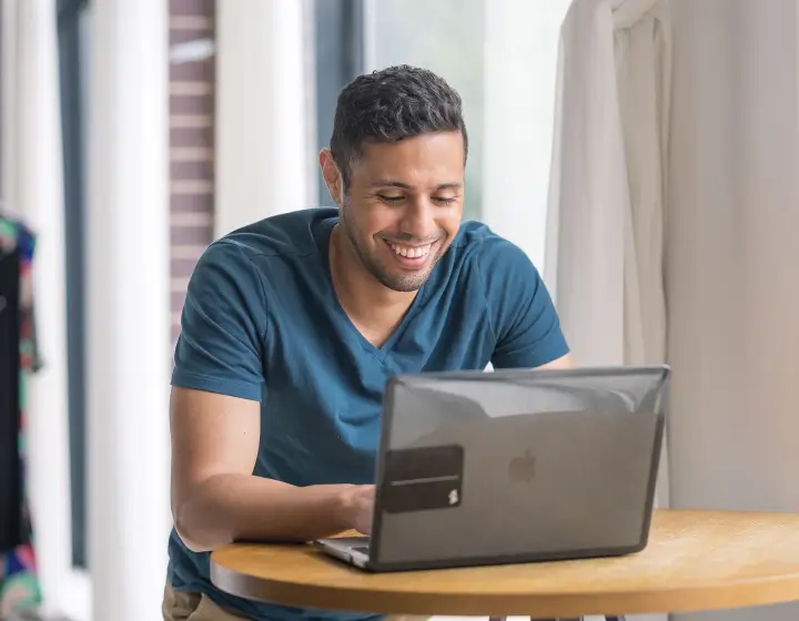 Collective member Elohim Pena looking at a laptop and smiling, Creative Director & Actor
