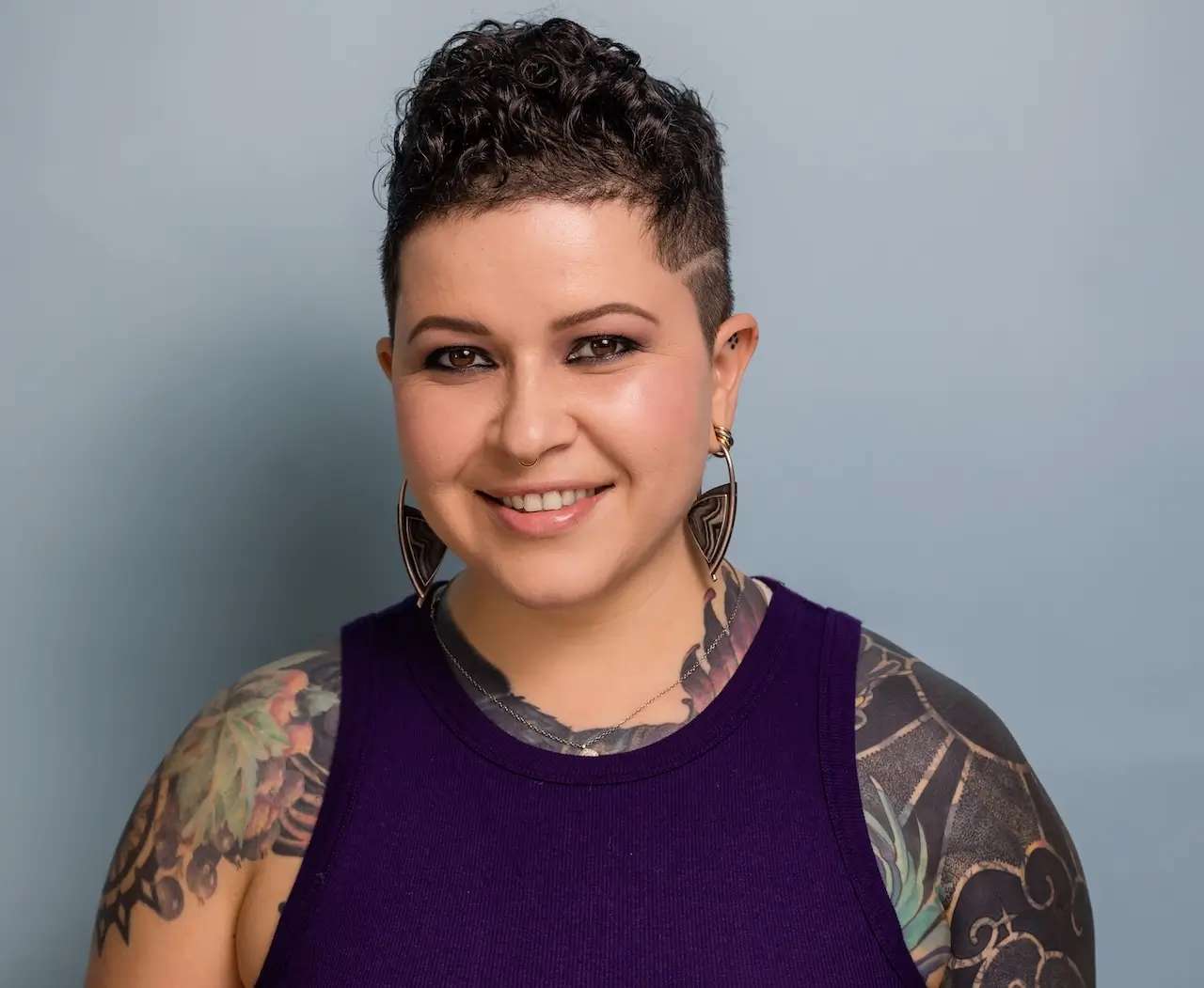 Portrait of Collective member Micah Riot, Tattoo Artist, smiling at the camera.