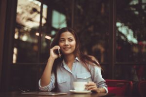 Image of woman talking on cell phone and drinking coffee