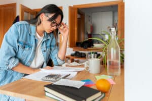 Entrepreneur Woman With Glasses Sitting Around The Table Doing Bill Accounts At Home.